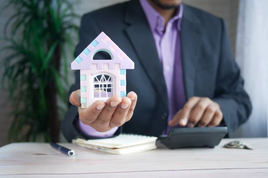 Person holding a toy house while calculating home fees