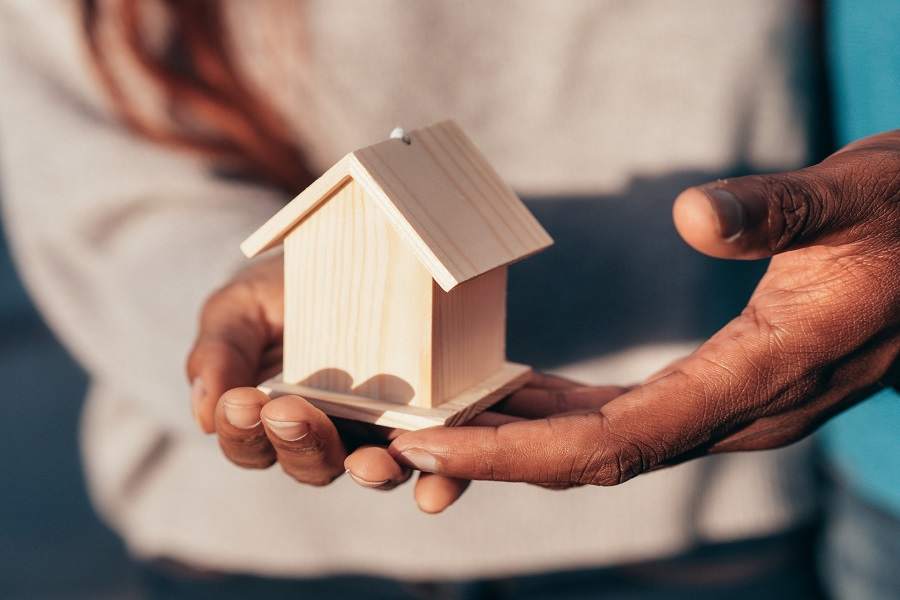 Two persons holding a miniature wooden house model