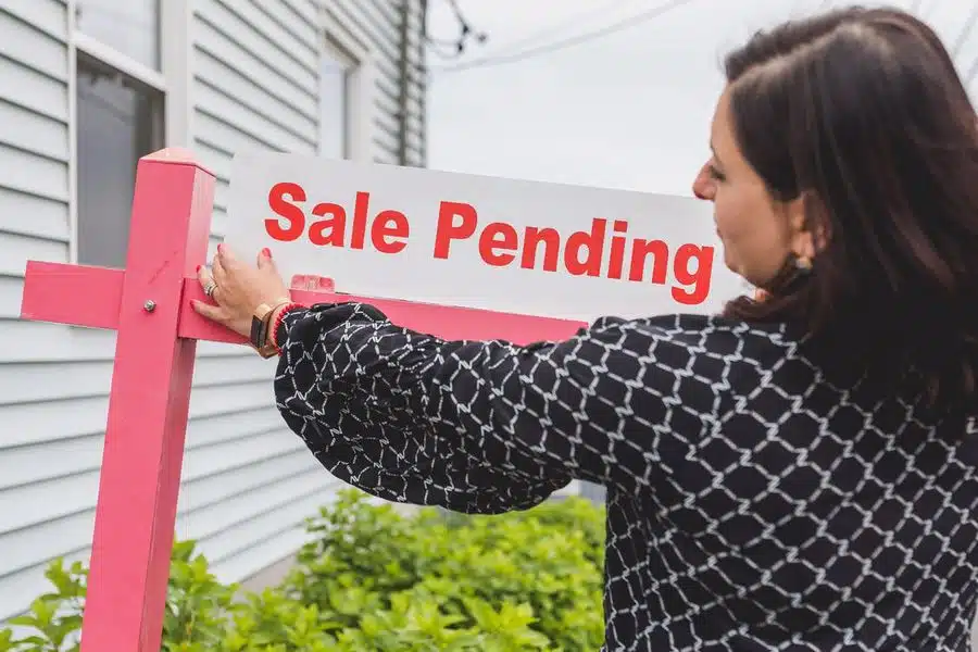 Realtor attaching a "sale pending" sign on a house that was no longer on the market