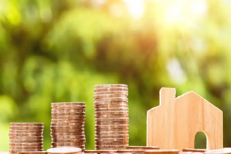Stacks of coins beside a wood carved house