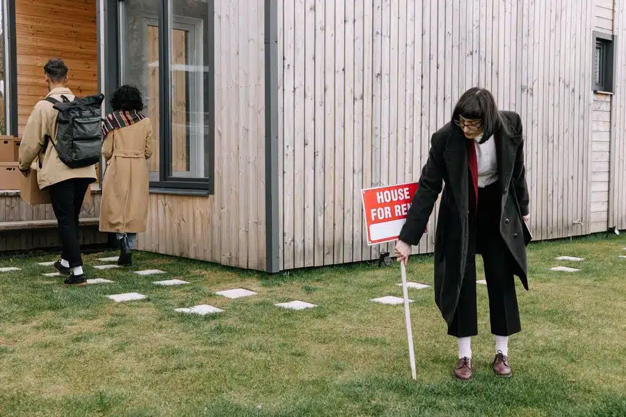 Real estate agent removing house for rent sign while a couple moves in with their boxes