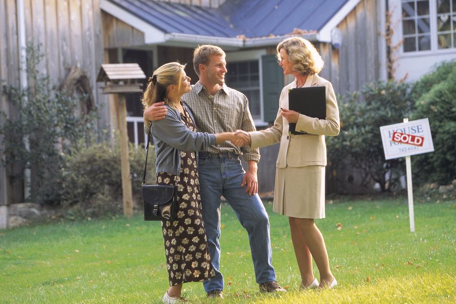 Realtor shaking the hands of a couple who just bought a house