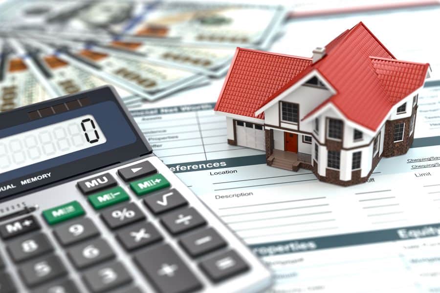 Calculator beside a miniature house model and legal papers