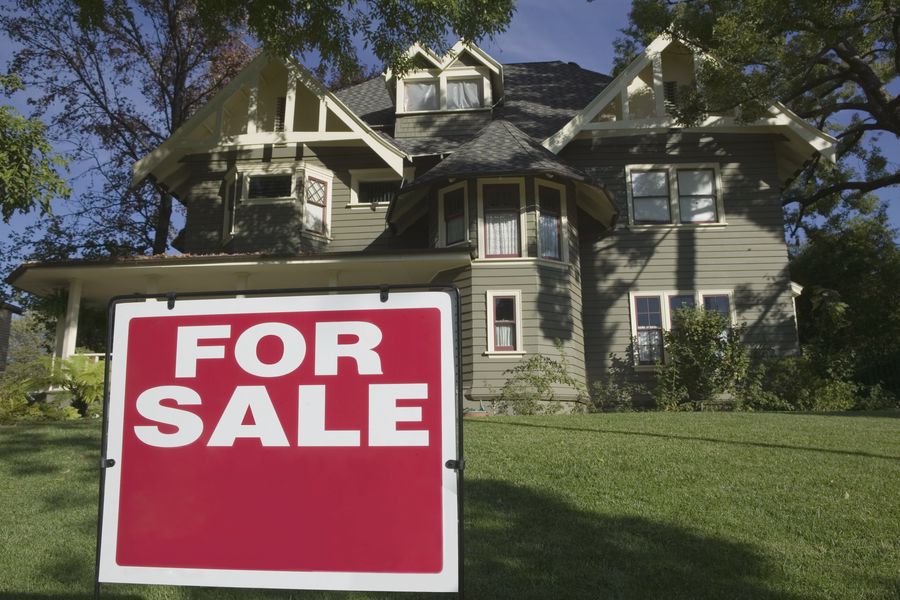 For Sale sign in front yard of house