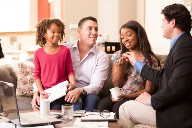 a mixed race couple with their daughter getting newly bought home keys from a real estate agent in black suit