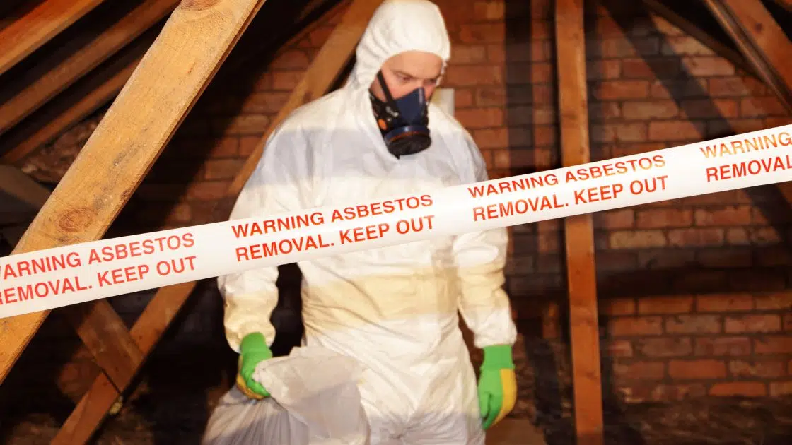 a man protective gear removing asbestos from a room