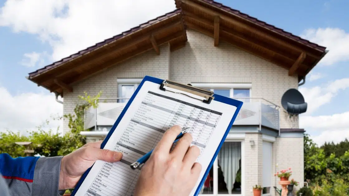 a home inspector with home inspection checklist in front of a house.