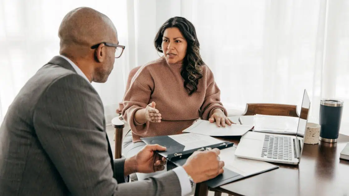 a black man in suit providing title insurance consultation to a woman
